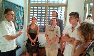 Ruslan Reyes, coordinador de la diaspora rusa en Cuba, presenta a los delegados la obra de jovenes pintores.